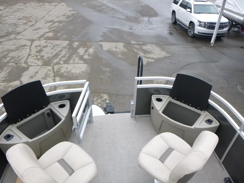 Slide: The Image of 2025 Sun Tracker Fishin' Barge 20 DLX with seating and storage, parked near a white SUV. - 18