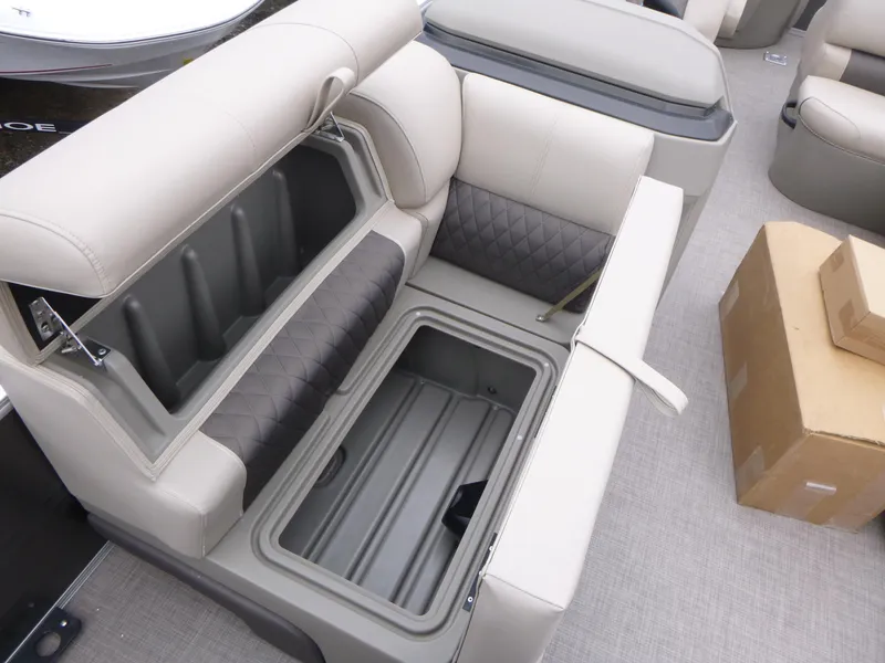 Slide: The Image of 2025 Sun Tracker Fishin' Barge 20 DLX storage compartment with cushioned seating and open lid. - 8