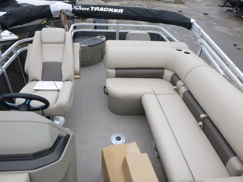 Slide: The Image of 2025 Sun Tracker Fishin' Barge 20 DLX interior with beige seating and steering console. - 9