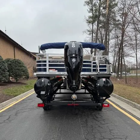 Slide: The Image of 2025 Ranger Reata 220FC pontoon boat on trailer, rear view, parked on a road. - 2