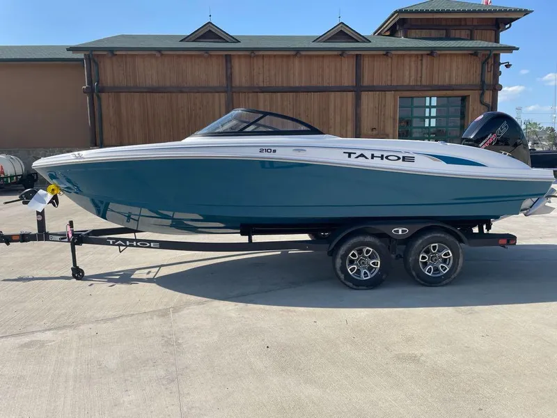 Slide: The Image of 2025 Tahoe 210 S boat on trailer, blue and white design, parked outdoors. - 0