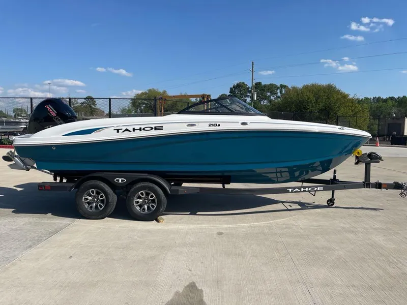 Slide: The Image of 2025 Tahoe 210 S boat on trailer, blue and white design, parked outdoors. - 1