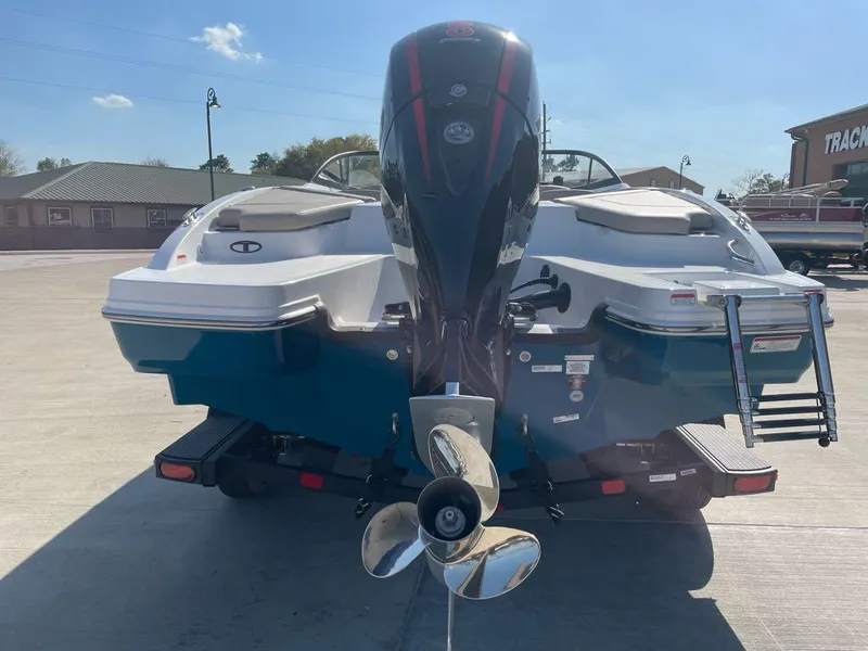 Slide: The Image of 2025 Tahoe 210 S boat, rear view with outboard motor and propeller, parked outdoors. - 3