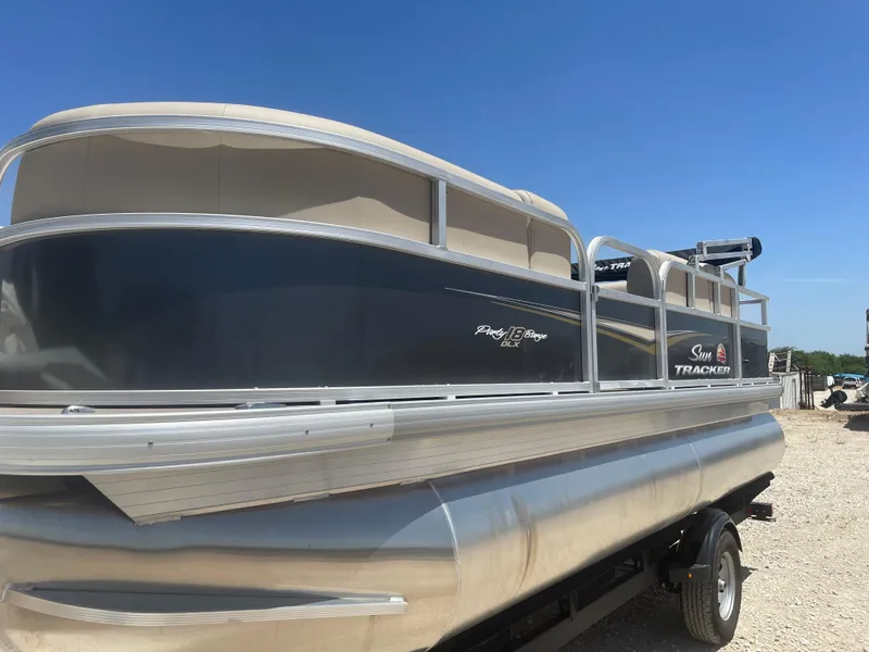 The Image of 2025 Sun Tracker Party Barge 18 DLX pontoon boat on trailer under clear blue sky. - 0