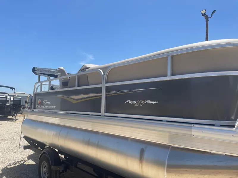 Slide: The Image of 2025 Sun Tracker Party Barge 18 DLX pontoon boat under clear blue sky. - 4