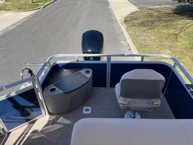 Slide: The Image of 2025 Sun Tracker Fishin' Barge 20 DLX pontoon boat with seating and motor, docked on pavement. - 7