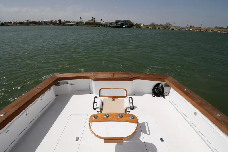 Slide: The Image of 1998 Huckins 70 Sportfish Convertible boat deck with wooden trim on open water. - 16