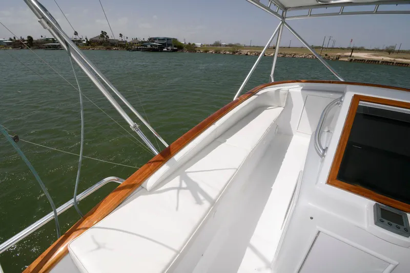 Slide: The Image of 1998 Huckins 70 Sportfish Convertible boat deck with wooden trim, overlooking calm waters. - 30