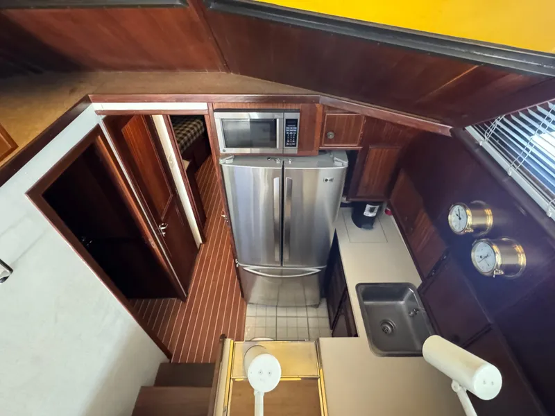 Slide: The Image of 1984 Hatteras 46 Convertible yacht kitchen with stainless steel appliances and wooden cabinetry. - 10