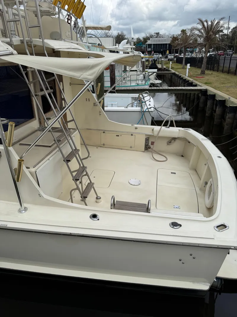 Slide: The Image of 1984 Hatteras 46 Convertible yacht docked, featuring spacious deck and ladder. - 26