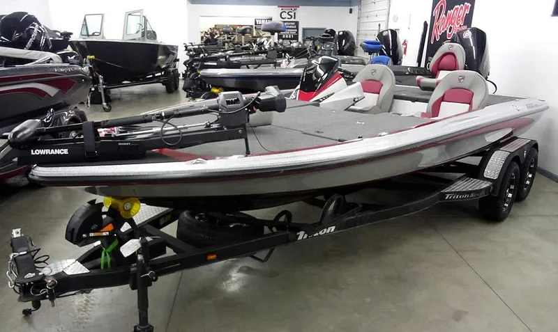 Slide: The Image of 2025 Triton 20XP Patriot fishing boat in showroom, featuring dual seats and advanced equipment. - 0