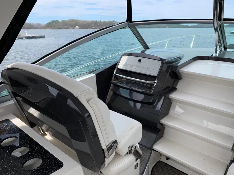 Slide: The Image of 2014 Monterey 320 Sport Yacht interior with helm and seating, overlooking serene water. - 19