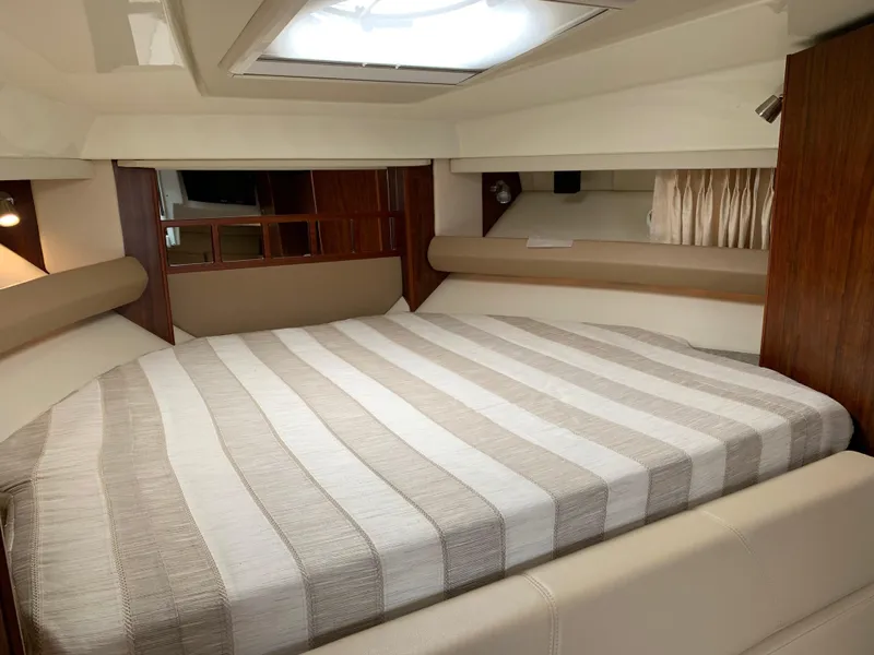 Slide: The Image of 2014 Monterey 320 Sport Yacht interior with striped bedding and wood accents. - 36