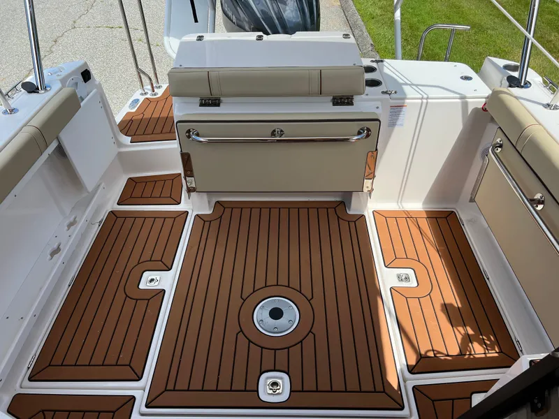 Slide: The Image of 2024 Ranger Tugs R-27 boat deck with teak flooring and cushioned seating. - 11