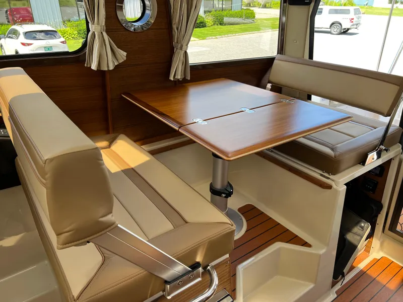 Slide: The Image of 2024 Ranger Tugs R-27 interior with wood table and beige seating. - 17