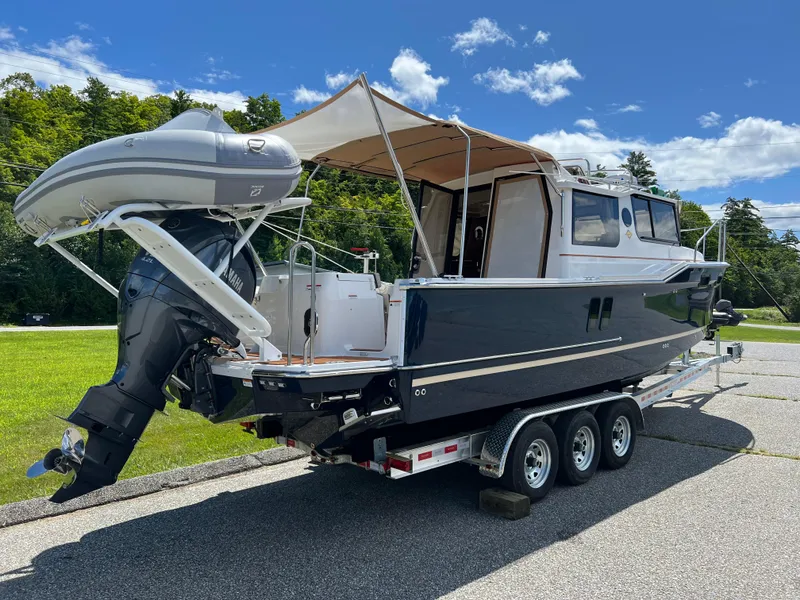 Slide: The Image of 2024 Ranger Tugs R-27 boat on trailer with canopy and outboard motor. - 2