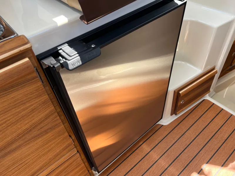 Slide: The Image of 2024 Ranger Tugs R-27 interior with stainless steel fridge and wood finish flooring. - 22