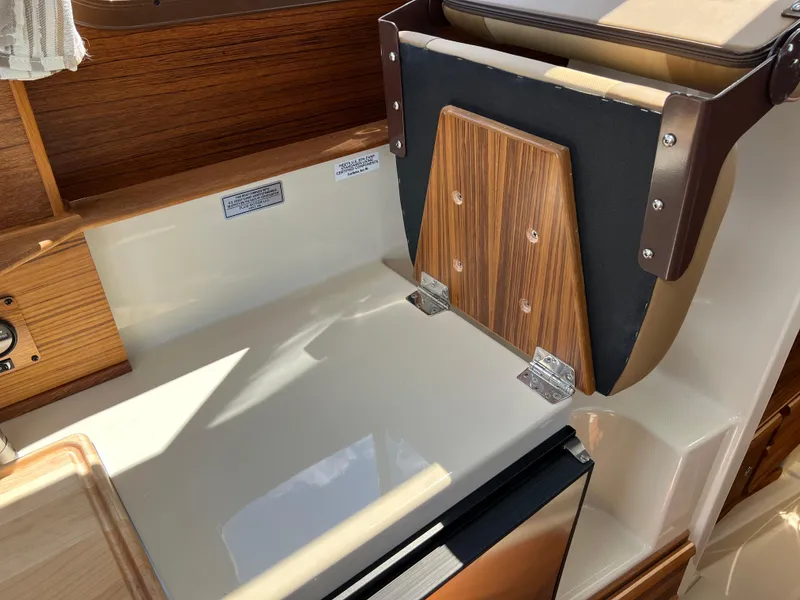 Slide: The Image of 2024 Ranger Tugs R-27 interior with wood accents and compact kitchen area. - 23