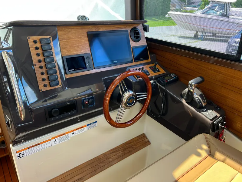 Slide: The Image of 2024 Ranger Tugs R-27 helm with wood accents and modern navigation controls. - 24