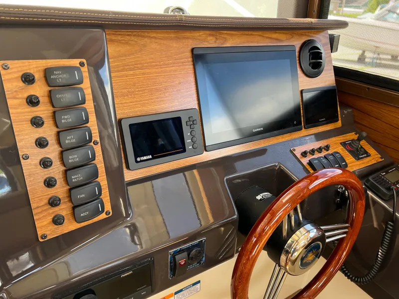 Slide: The Image of 2024 Ranger Tugs R-27 dashboard with wood accents and modern navigation controls. - 25