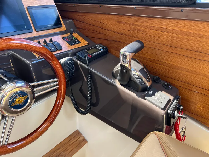 Slide: The Image of 2024 Ranger Tugs R-27 helm with wooden dashboard, steering wheel, and control panel. - 26