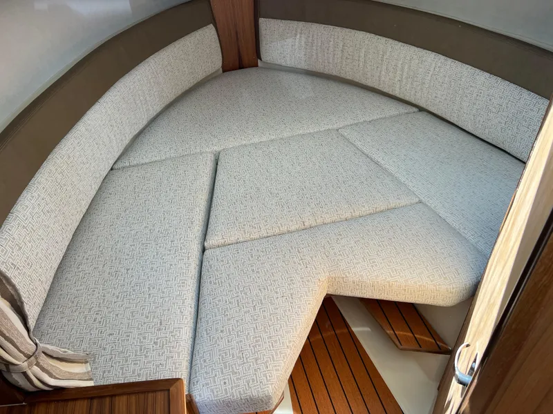 Slide: The Image of 2024 Ranger Tugs R-27 interior cabin with cushioned seating and wooden flooring. - 27