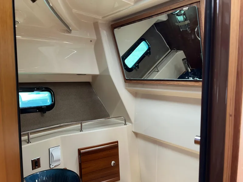 Slide: The Image of 2024 Ranger Tugs R-27 interior cabin with mirror and porthole window. - 29