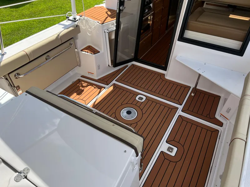 Slide: The Image of 2024 Ranger Tugs R-27 boat interior with teak flooring and cushioned seating. - 5