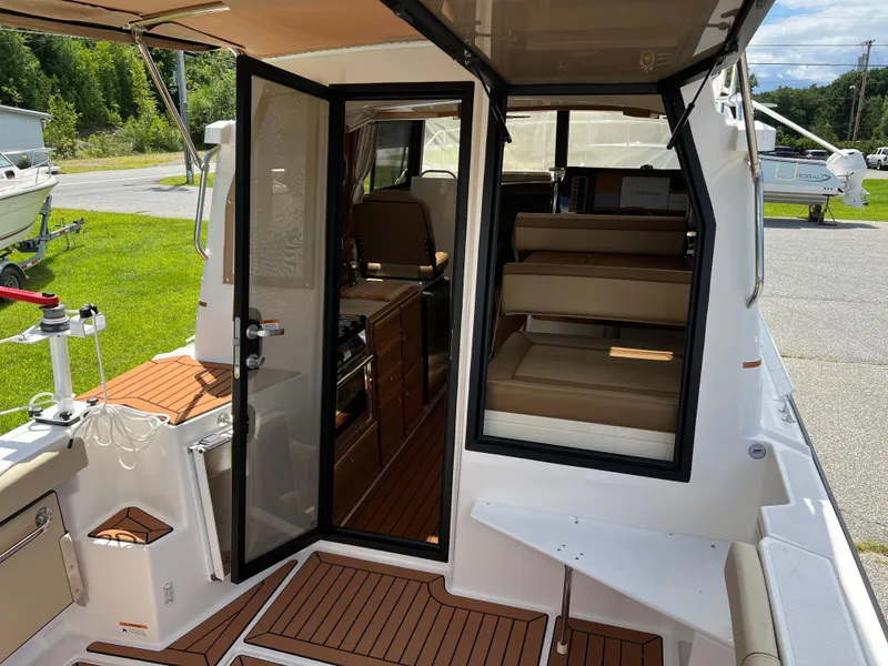 Slide: The Image of 2024 Ranger Tugs R-27 boat interior with open door, showcasing seating and wood flooring. - 6