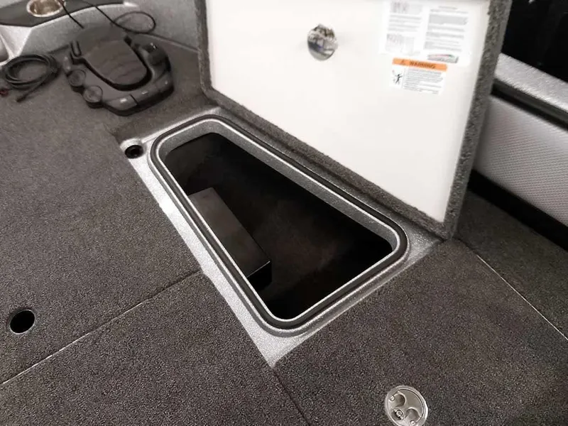 Slide: The Image of 2025 Ranger 1880MS Angler boat storage compartment with open lid and carpeted interior. - 15