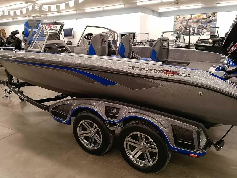 The Image of 2025 Ranger 620FS Fisherman boat on display in showroom, featuring sleek design and dual-axle trailer. - 1