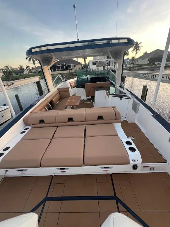 Slide: The Image of 2023 Aviara AV32 OB boat with spacious deck, tan seating, and modern design at a marina. - 2