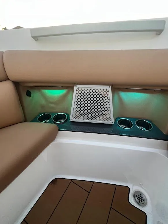 Slide: The Image of 2023 Aviara AV32 OB boat interior with beige seating, cup holders, and ambient lighting. - 23