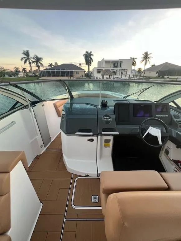 Slide: The Image of 2023 Aviara AV32 OB boat interior with modern dashboard, overlooking waterfront homes and palm trees. - 6