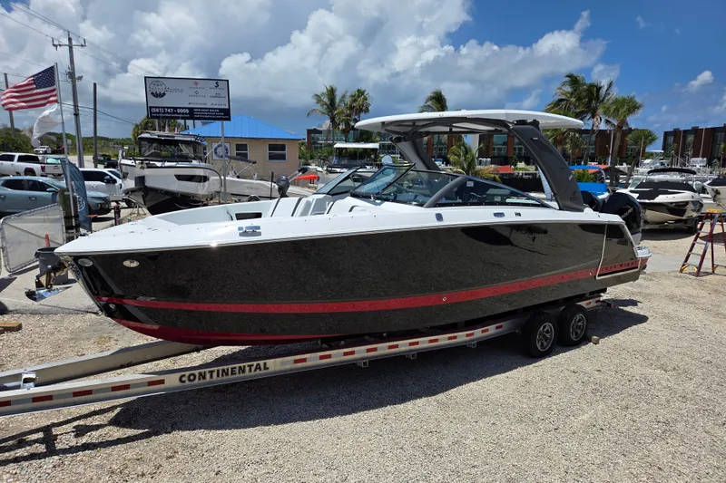 Slide: The Image of 2025 Four Winns H9 OB boat on trailer, displayed outdoors under a sunny sky. - 1