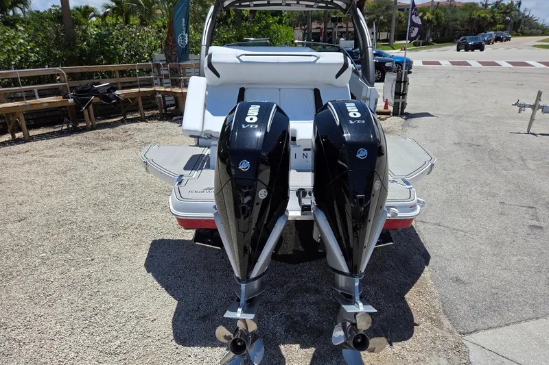 Slide: The Image of 2025 Four Winns H9 OB boat with dual outboard engines, parked on gravel. - 21