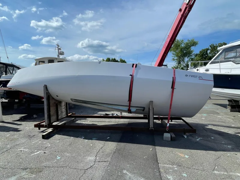 Slide: The Image of 2025 Beneteau First 24 sailboat on a stand, secured with red straps, under a clear sky. - 8