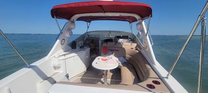 Slide: The Image of 2006 Fountain 38 Express Cruiser with red canopy, spacious seating, and table on calm water. - 3