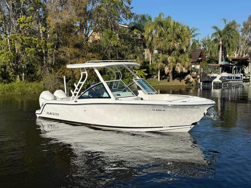 Slide: The Image of 2021 Blackfin 252DC boat on calm water, surrounded by lush greenery and clear blue sky. - 10