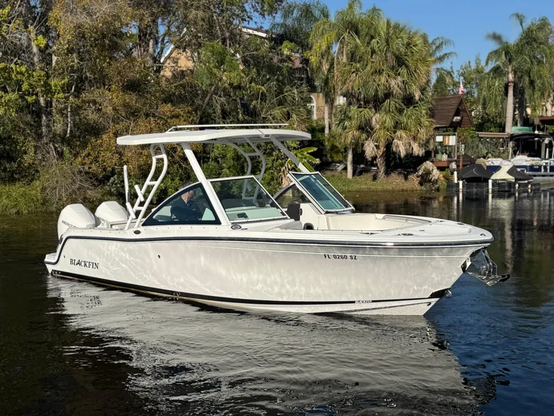 Slide: The Image of 2021 Blackfin 252DC boat cruising on a calm river with lush greenery. - 11