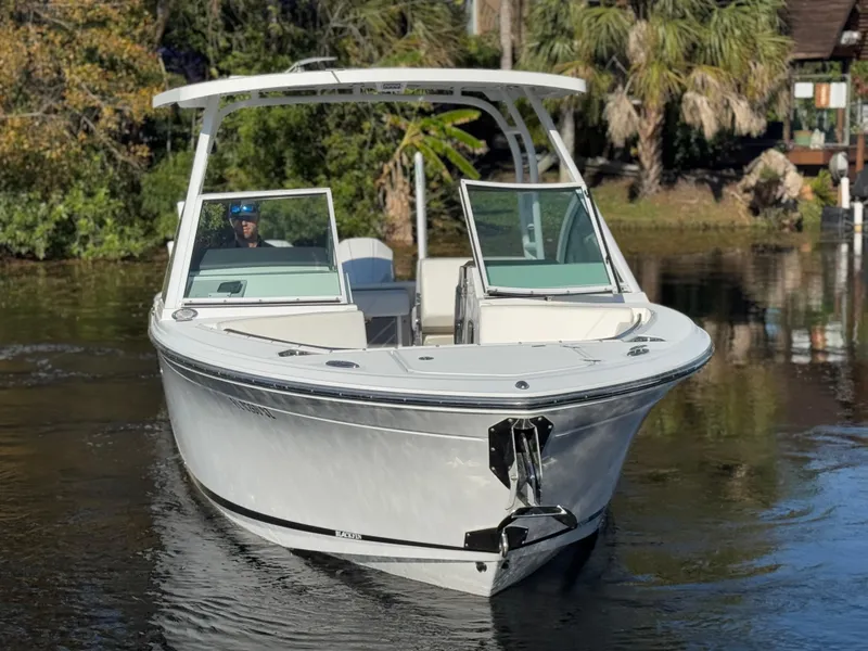 Slide: The Image of 2021 Blackfin 252DC boat on calm water, surrounded by lush greenery. - 14