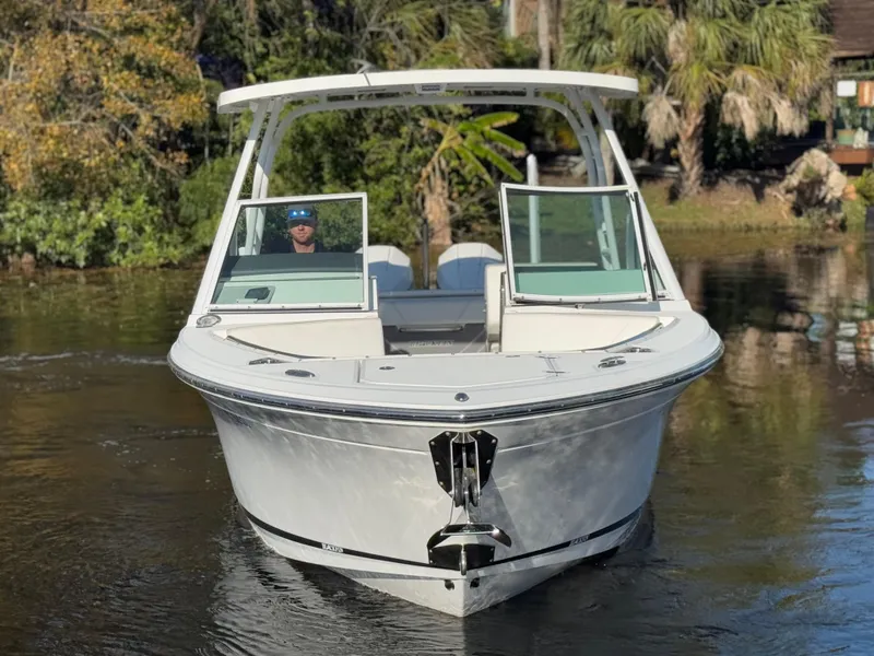 Slide: The Image of 2021 Blackfin 252DC boat on calm water, surrounded by lush greenery. - 16
