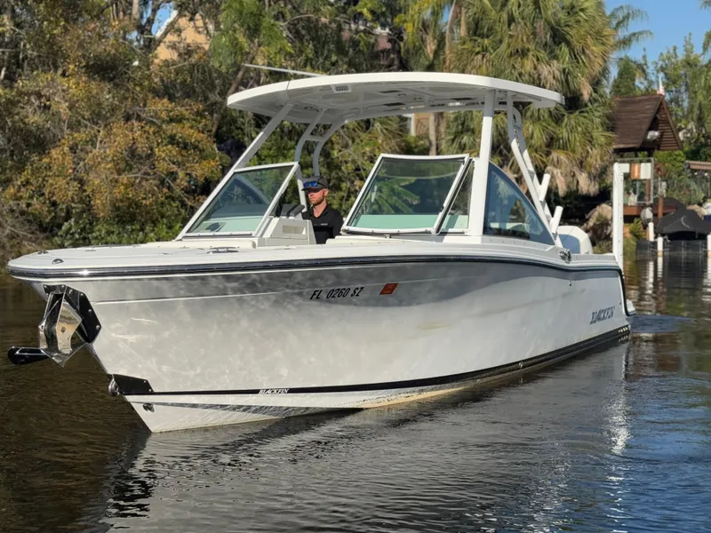 Slide: The Image of 2021 Blackfin 252DC boat on calm water with lush greenery in the background. - 18