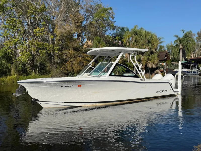 Slide: The Image of 2021 Blackfin 252DC boat on a calm river, surrounded by lush greenery. - 21