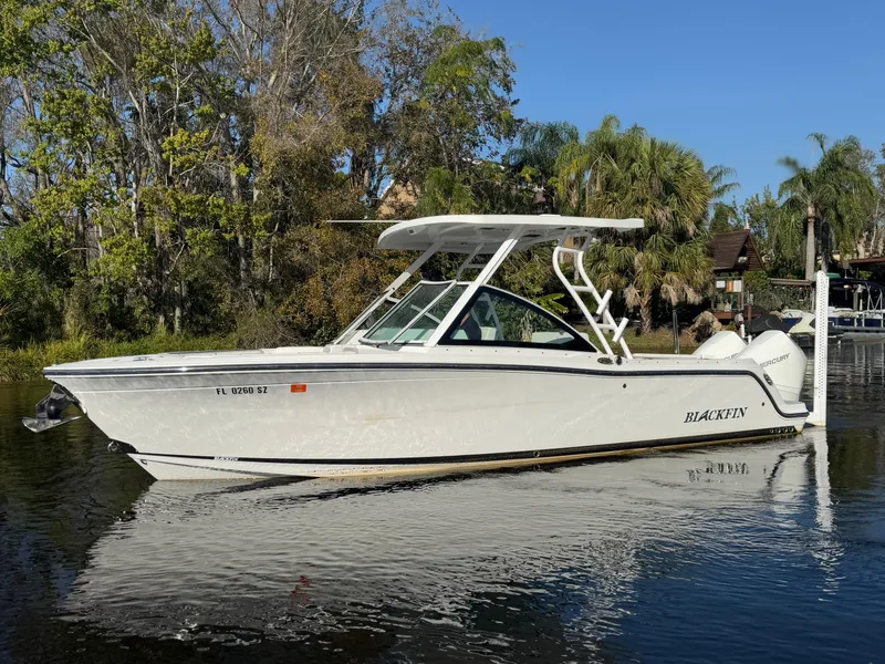 Slide: The Image of 2021 Blackfin 252DC boat on calm water, surrounded by lush greenery. - 22