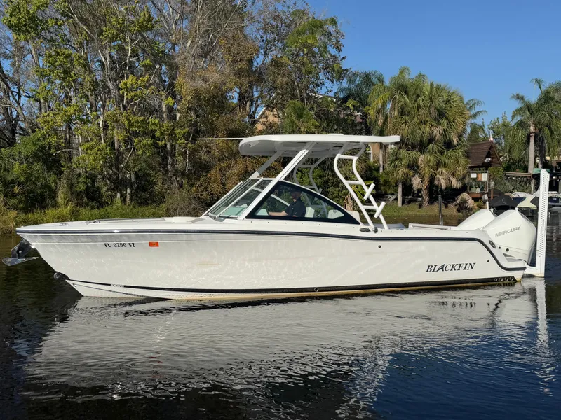 Slide: The Image of 2021 Blackfin 252DC boat on calm water, surrounded by lush greenery. - 23