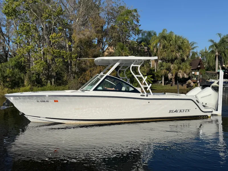 Slide: The Image of 2021 Blackfin 252DC boat on calm water, surrounded by lush greenery. - 24