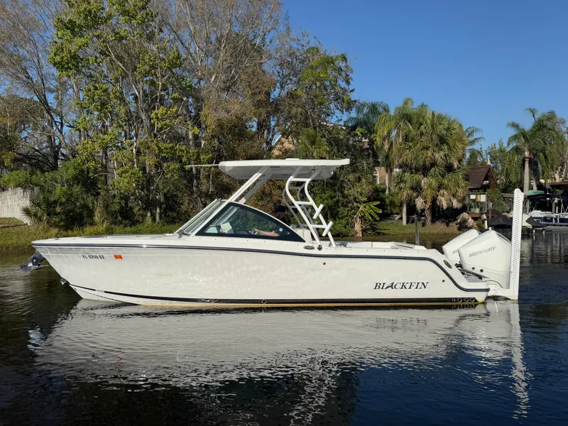 Slide: The Image of 2021 Blackfin 252DC boat on calm water, surrounded by lush greenery. - 25