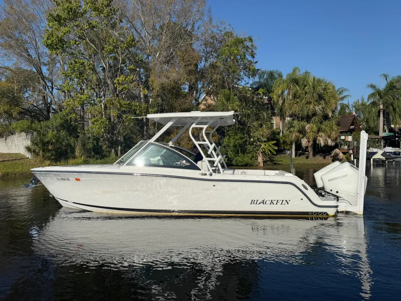 Slide: The Image of 2021 Blackfin 252DC boat on calm water, surrounded by lush greenery. - 26