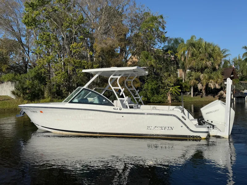 Slide: The Image of 2021 Blackfin 252DC boat on calm water, surrounded by lush greenery. - 27